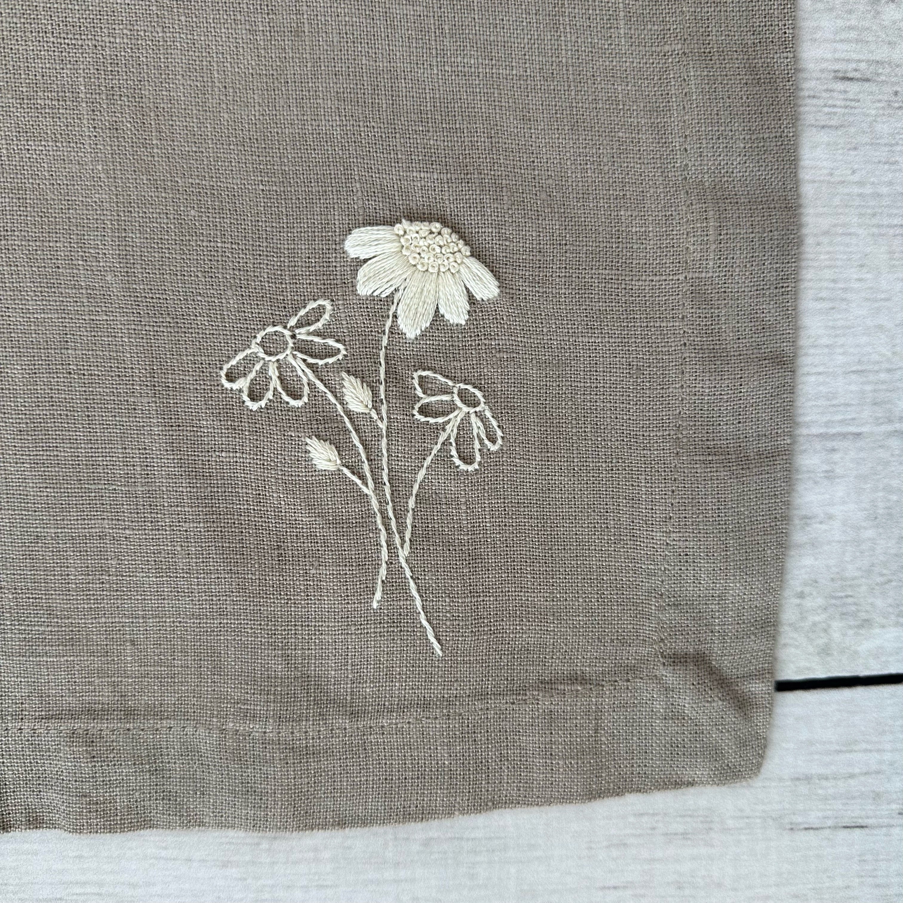 Embroidered flowers on a taupe linen placemat corner