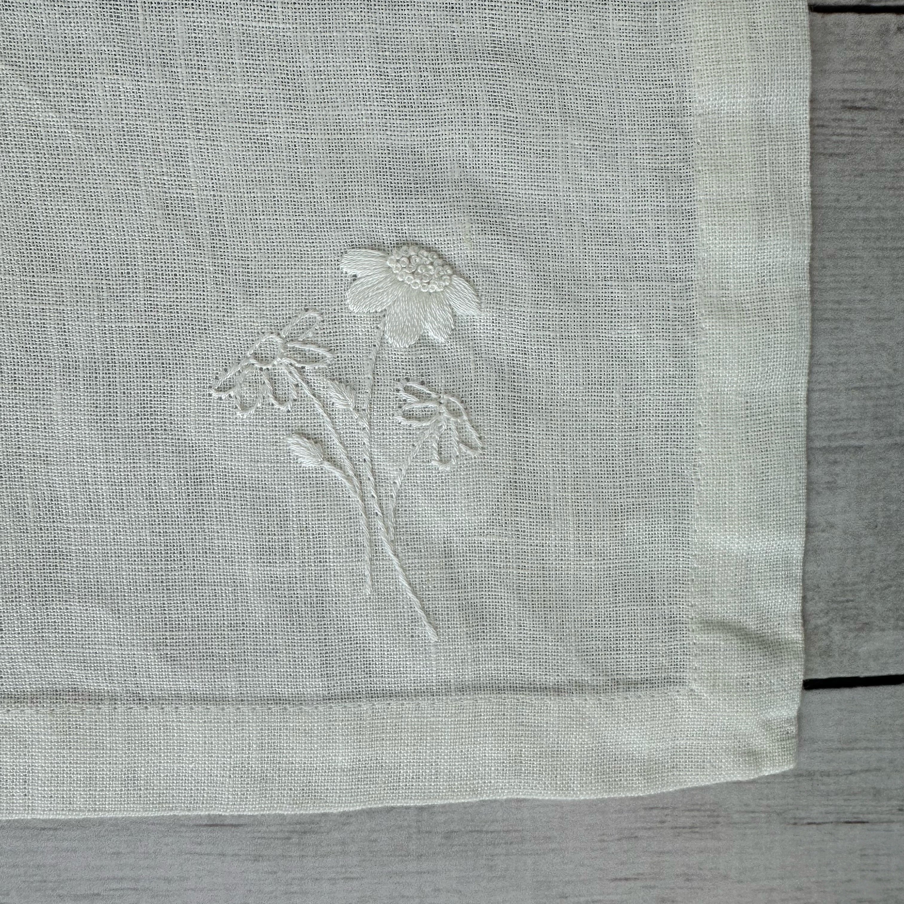 Embroidered flowers on an ivory linen placemat corner