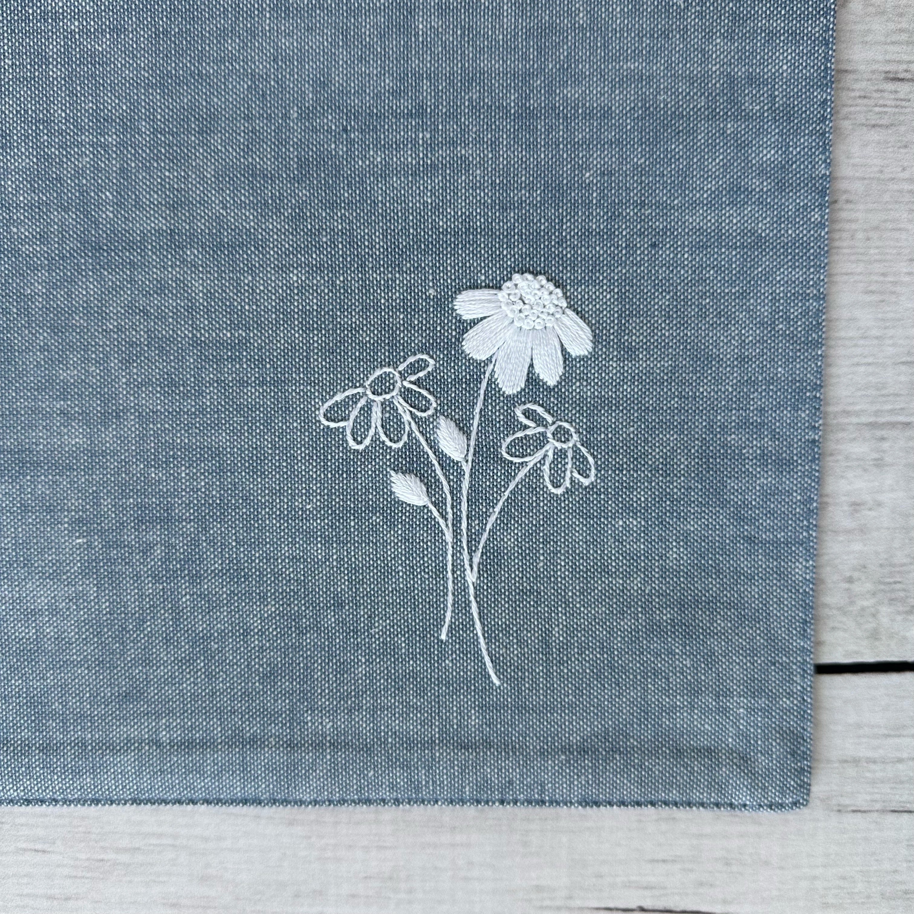 Floral embroidery on corner of a blue cotton placemat