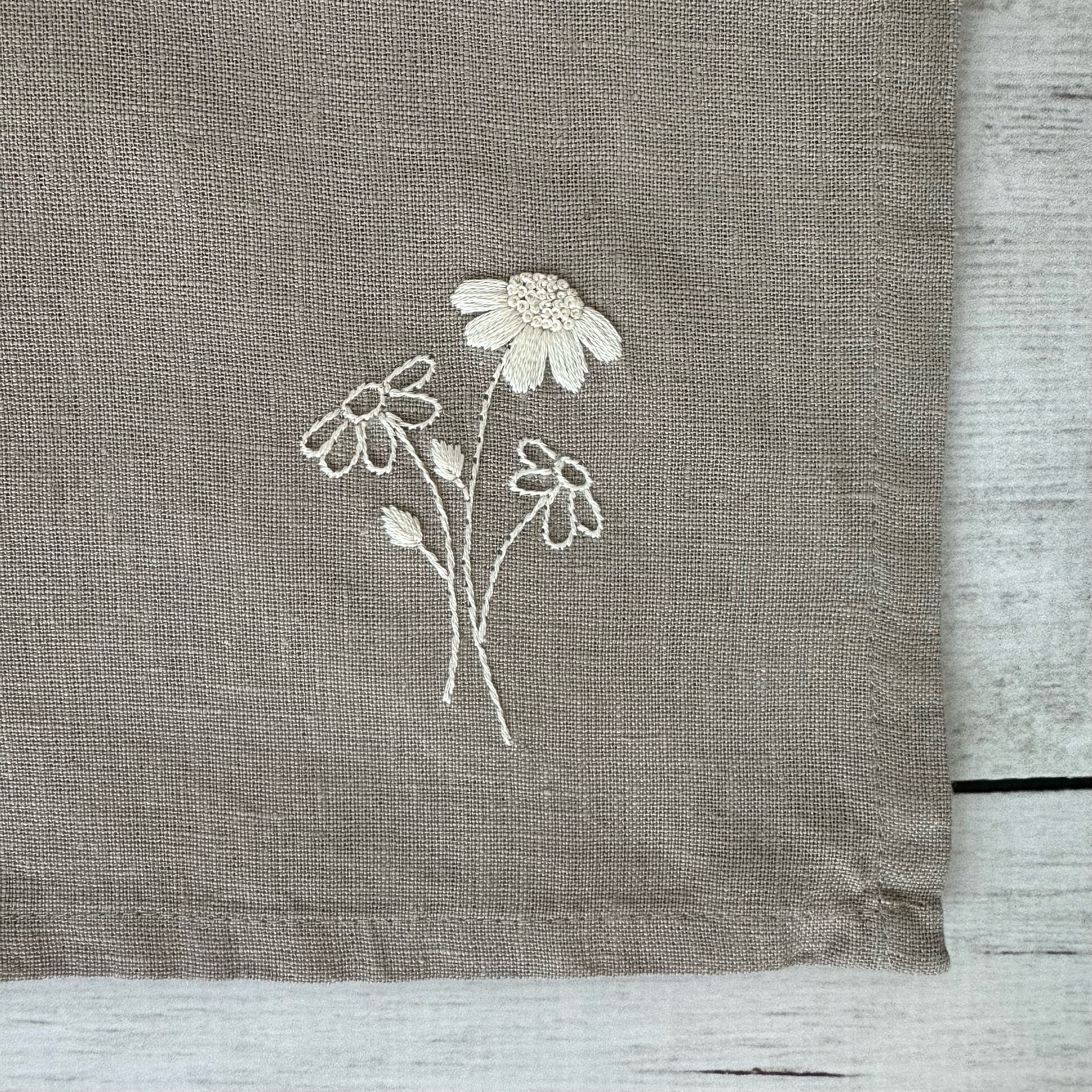 Floral embroidered design on corner of a taupe linen napkin