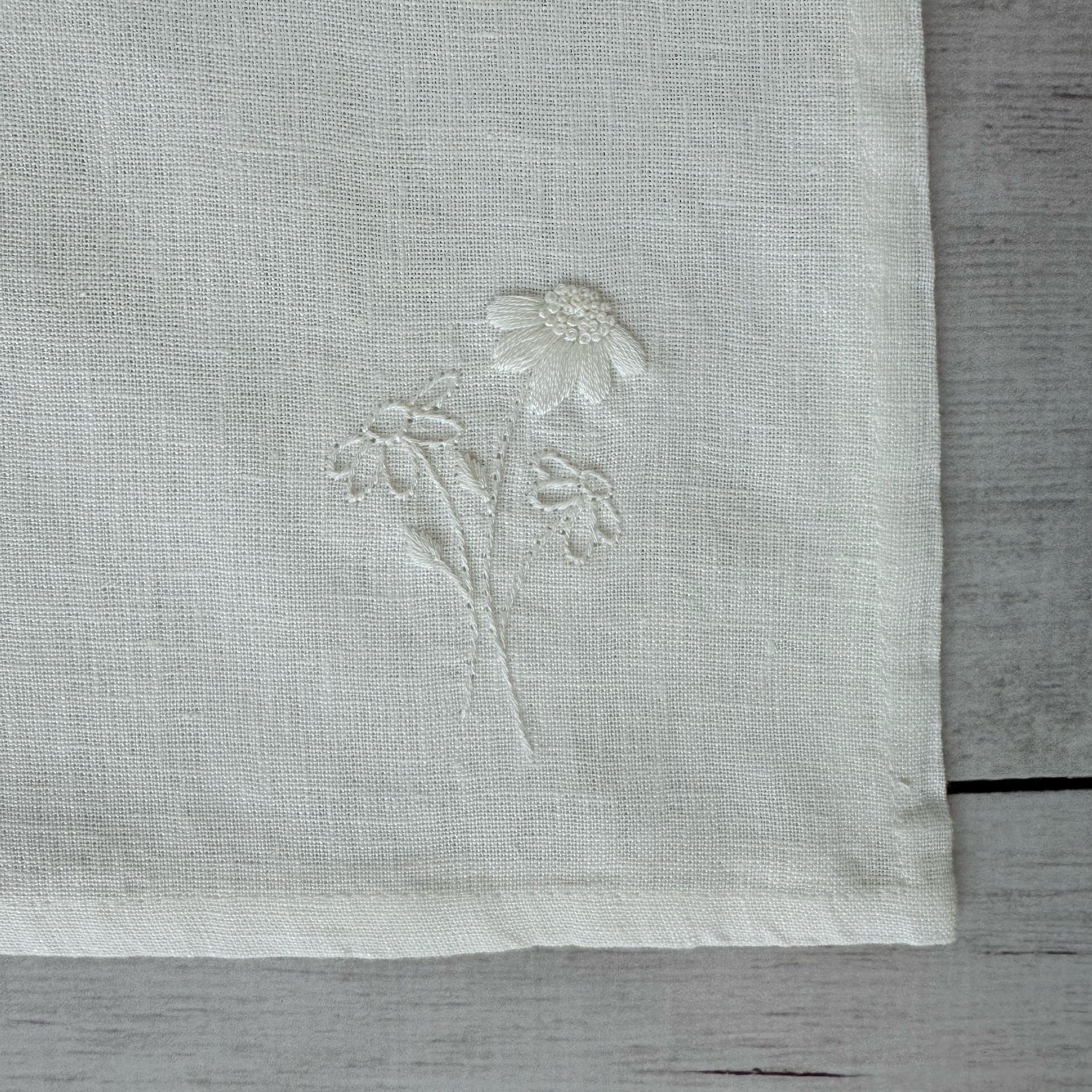 Floral embroidered design on corner of an ivory linen napkin