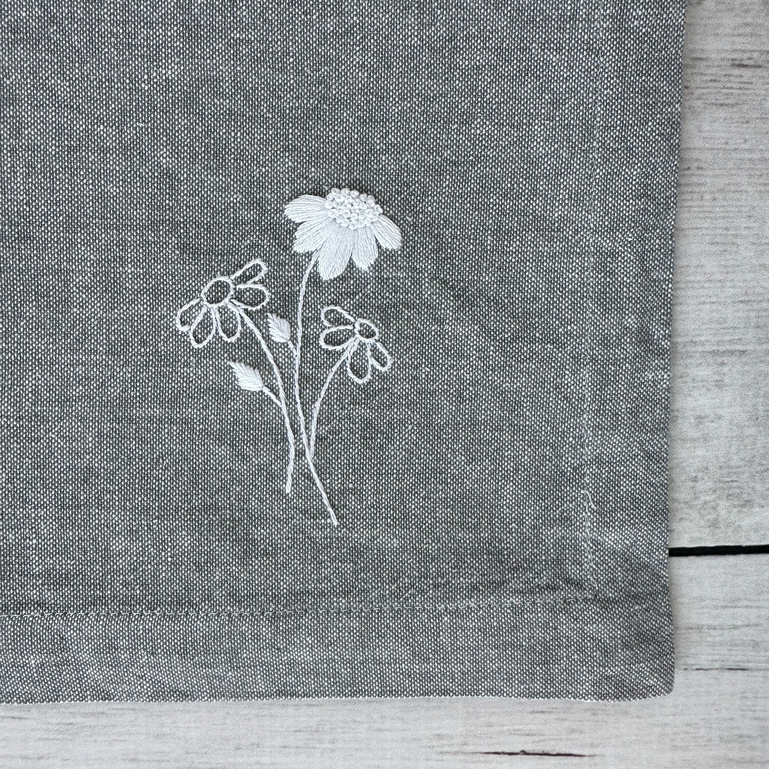 Embroidered flowers on a gray cotton napkin corner