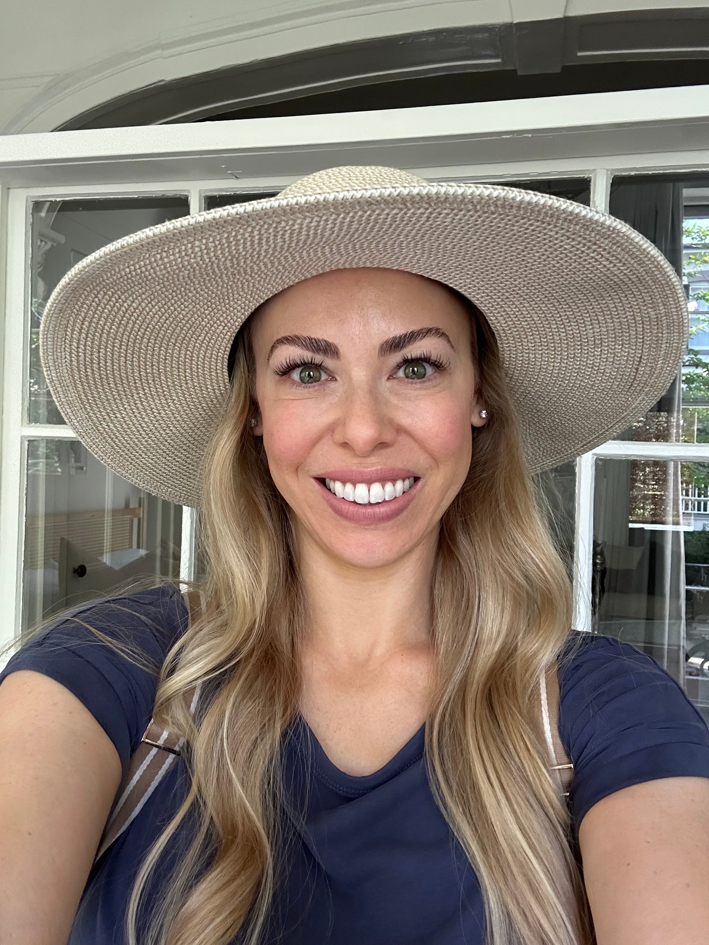 Woman wearing a wide-brimmed hat and smiling.