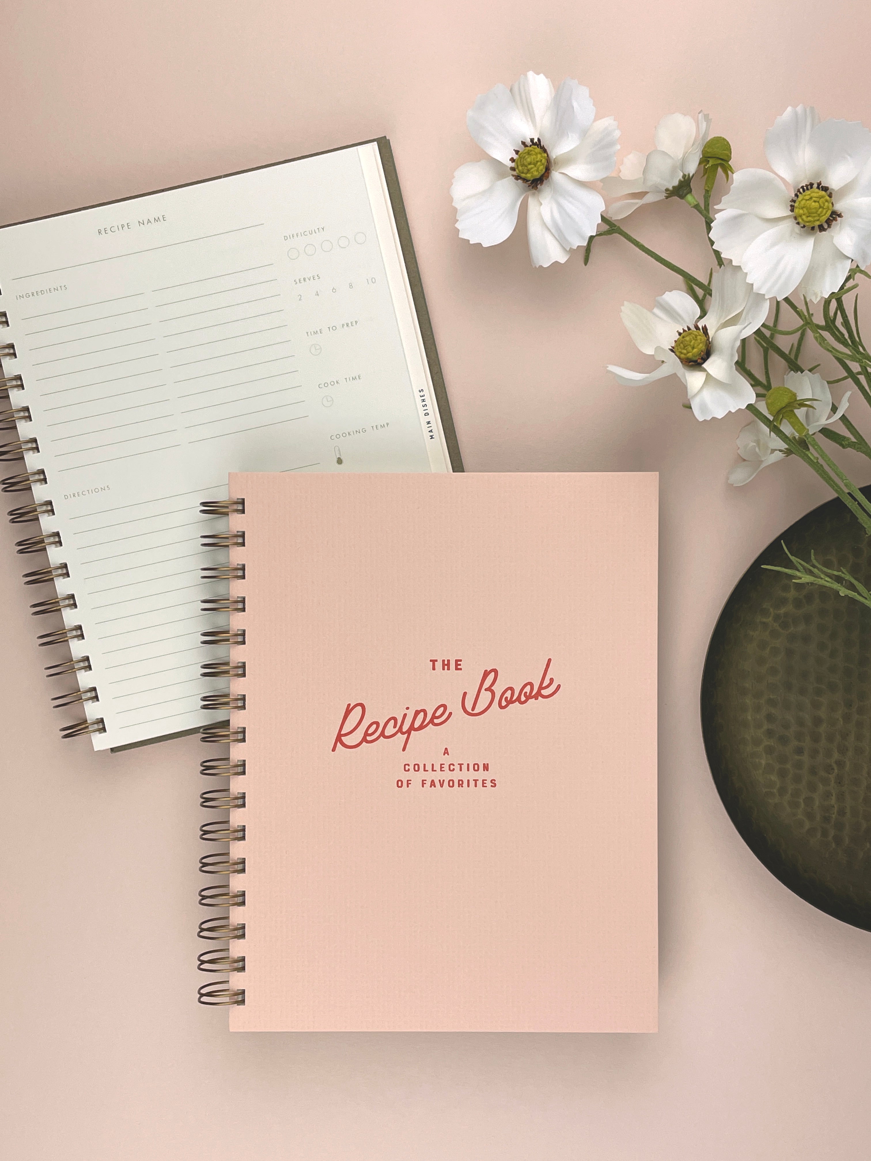 Pink recipe book with a white flower arrangement on a light background
