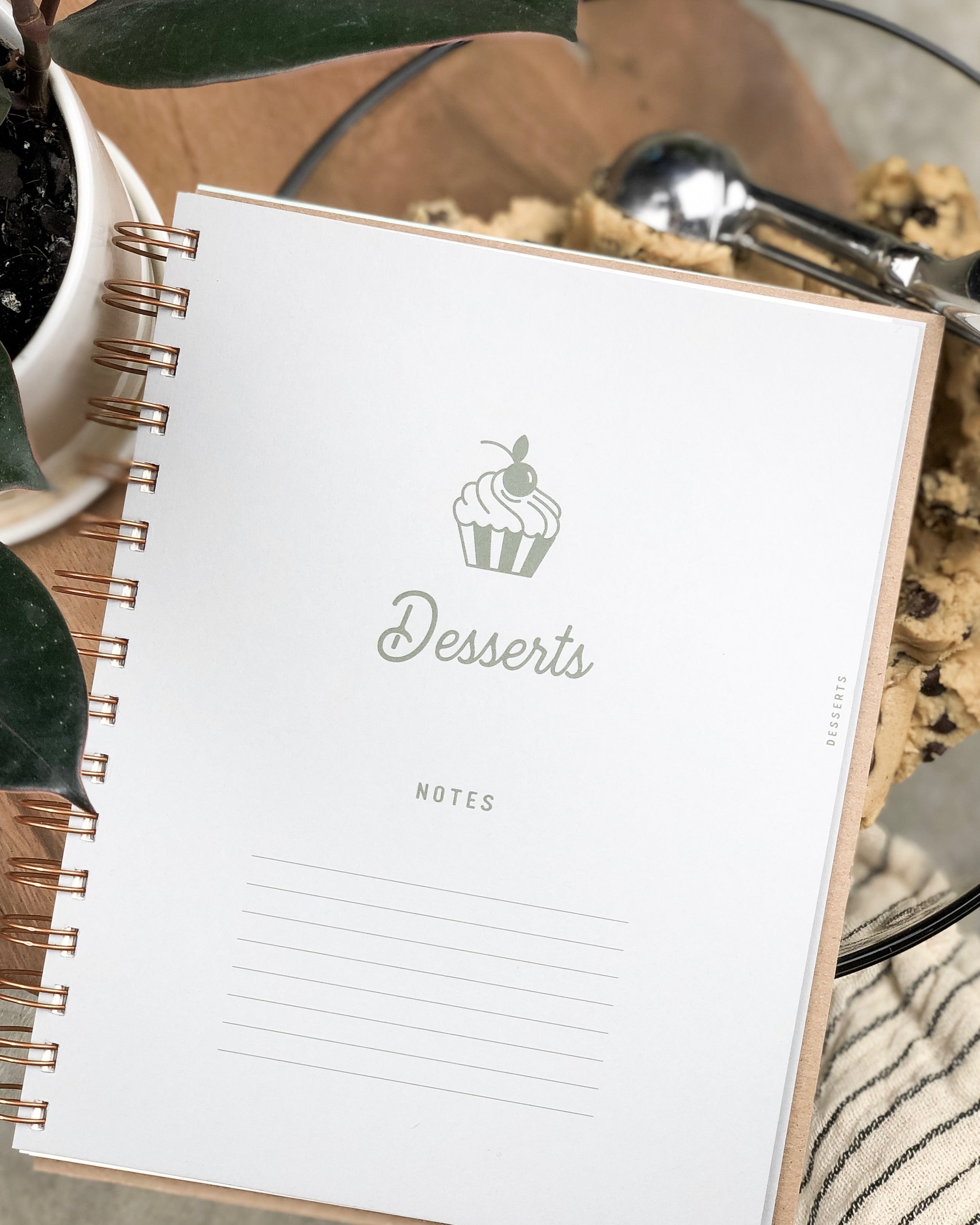 Desserts page of recipe book on a table with cookies and a plant.