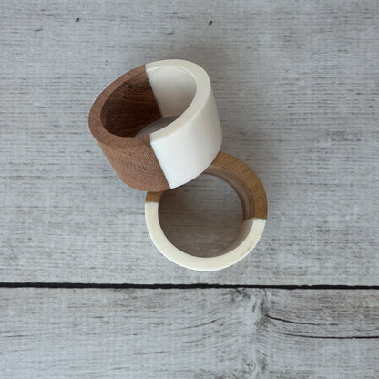 Two wooden napkin rings with white accents on a wooden surface