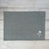 Gray cotton placemat with embroidered  floral design on a wooden surface