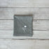 Gray cotton napkin with floral embroidered design on a wooden surface