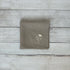 Taupe linen napkin with floral embroidered design on a wooden surface