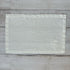 Ivory linen placemat with embroidered flowers on a wooden surface