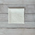 Ivory linen napkin with floral embroidered design on a wooden surface