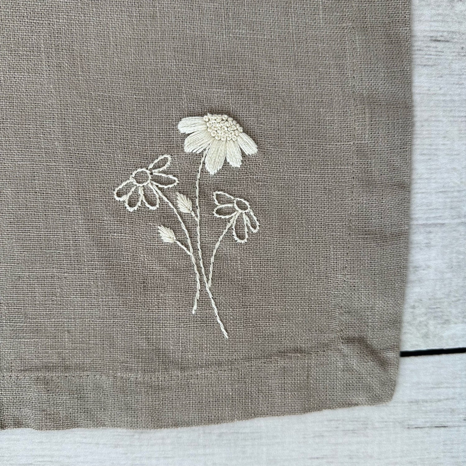 Embroidered flowers on a taupe linen placemat corner