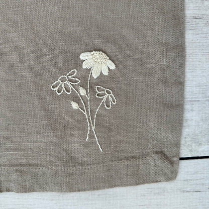 Embroidered flowers on a taupe linen placemat corner