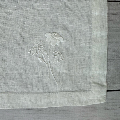 Embroidered flowers on an ivory linen placemat corner