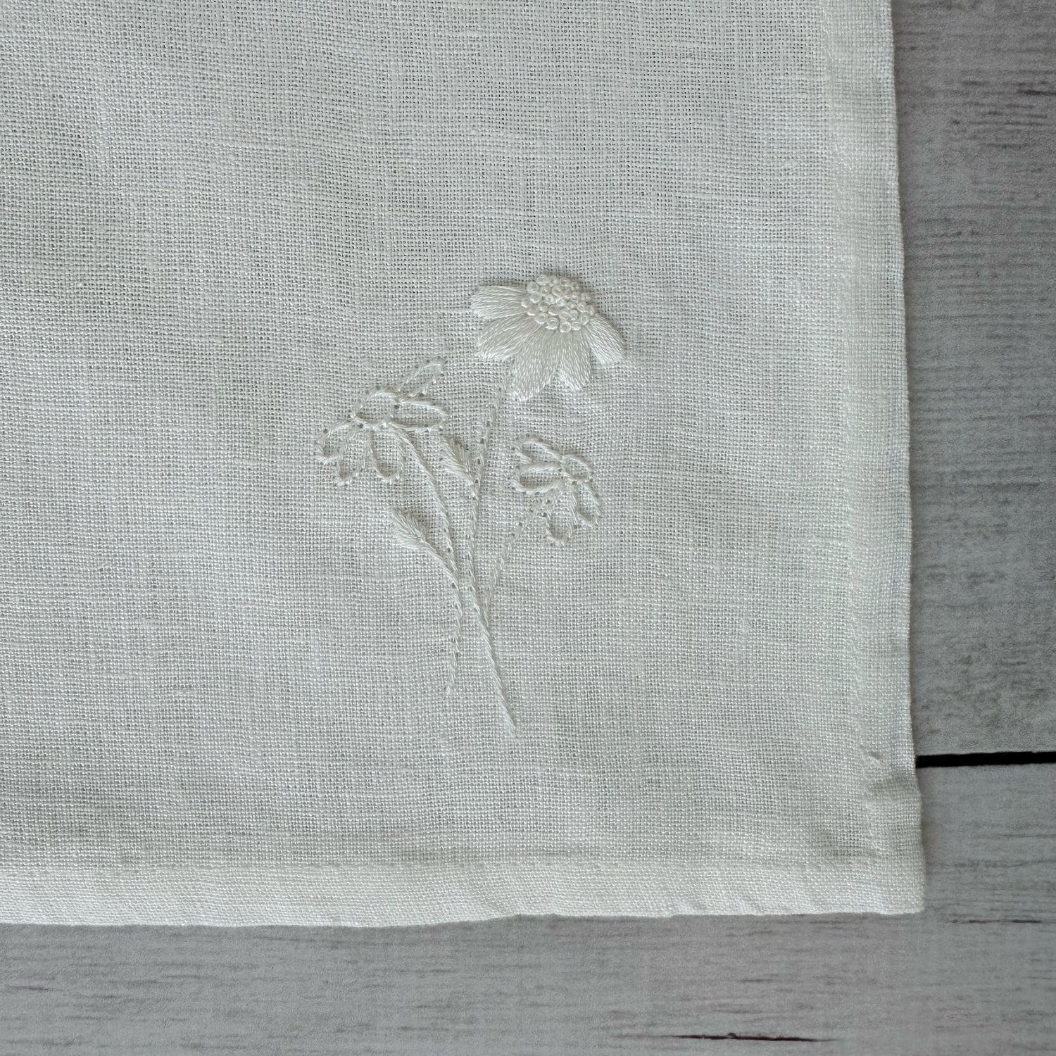 Floral embroidered design on corner of an ivory linen napkin