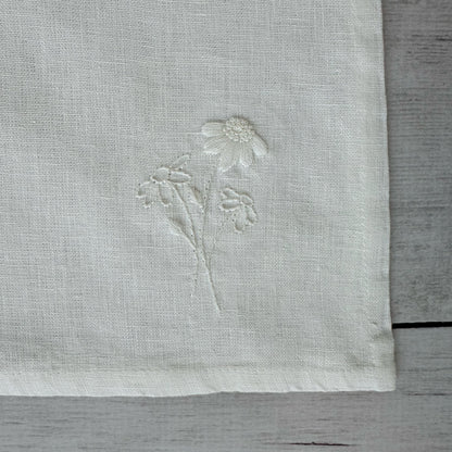 Floral embroidered design on corner of an ivory linen napkin