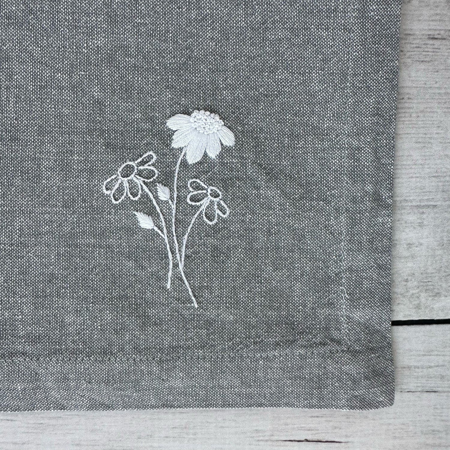 Embroidered flowers on a gray cotton napkin corner