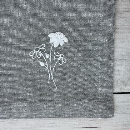 Embroidered flowers on a gray cotton napkin corner
