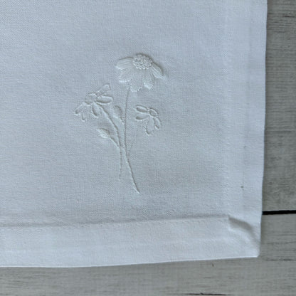 Floral embroidered design on corner of a white cotton napkin