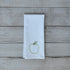 White tea towel with embroidered green apple design on a wooden surface