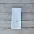 White tea towel with an embroidered yellow apple design on a wooden surface