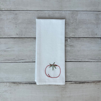 White tea towel with a tomato design on a wooden surface