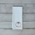 White tea towel with a tomato design on a wooden surface