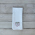 White tea towel with embroidered strawberry design on a wooden surface