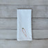 White tea towel with embroidered carrot design on a wooden surface