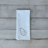 White tea towel with embroidered avocado design on a wooden surface