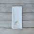 White tea towel with lemon embroidery on a wooden surface