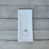 White tea towel with embroidered peach design on a wooden surface