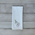 White tea towel with embroidered cherry design on a wooden surface