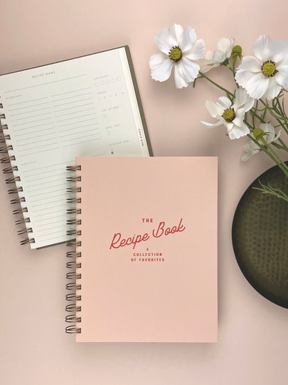 Pink recipe book with a white flower arrangement on a light background